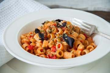 Close up of tomato sause pasta and basil in a white plate.