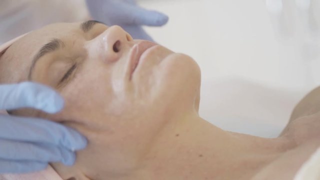 Woman getting massage of face after botox injections in the beauty salon