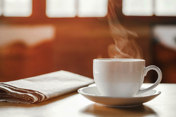 coffee cup with newspaper on the table, coffee shop background, warm tone - Powered by Adobe
