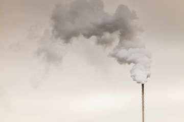 Smoke from chimney on dark cloudy sky