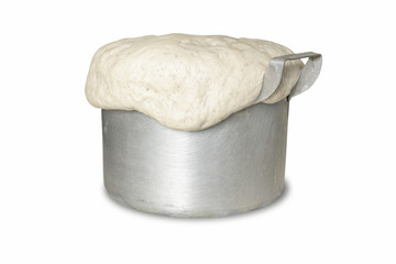 Aluminum pan overflowed with dough close-up on a white background.