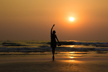 Ballet dancer's silhouette by the sea in sunset light in Arambol beach, North Goa, India