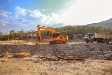 Track-type loader excavator machine doing earthmoving work at construction site on sunset background