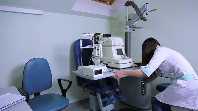 ophthalmologist checks sight of patient with refractometer