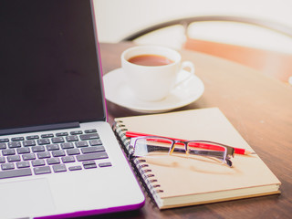 Workplace with laptop coffee and book on wooden desk.