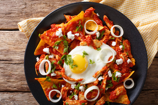 Mexican breakfast: chilaquiles with egg and chicken close-up. horizontal top view