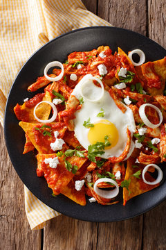 Mexican breakfast: chilaquiles with egg and chicken close-up. Vertical top view