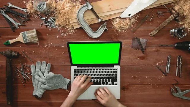Top view craftsman hands working laptop computer with green screen