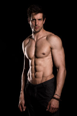 Fototapeta premium Strong muscular athlete posing on black