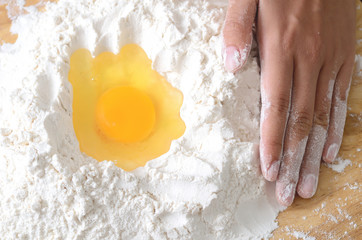 Pouring egg yolk mixing with flour to making bread or cake,bakery cooking