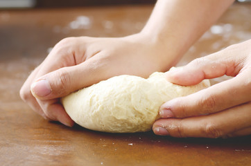 Bread cooking,kneading bread dough on wooden board by hand