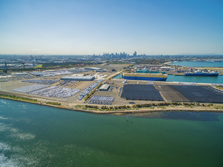 aerial view of Yarra River and large imported cars parking lots near Port Melbourne, with CBD...