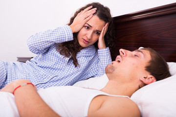 Awake woman watching snorring husband at night