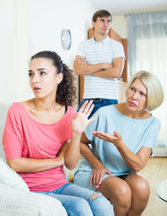 Relatives quarrelling with young woman in domestic interior