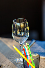 A glass of wine and some pencils is on the table in the restaurant. Illustration for the theme "children in the restaurant." © milanchikov