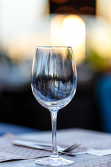 Wine glass stands on the table in the restaurant. Evening, the setting sun.