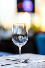 Wine glass stands on the table in the restaurant. Evening, the setting sun.