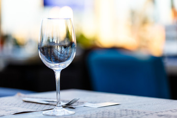 Wine glass stands on the table in the restaurant. Evening, the setting sun.