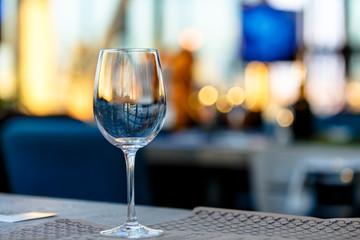 Wine glass stands on the table in the restaurant. Evening, the setting sun.