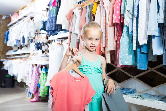 portrait of  girl standing in kids clothes store with shopping bags