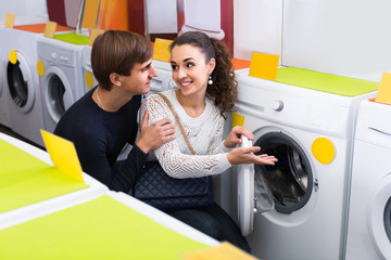 couple choosing washing machine in hypermarket and smiling