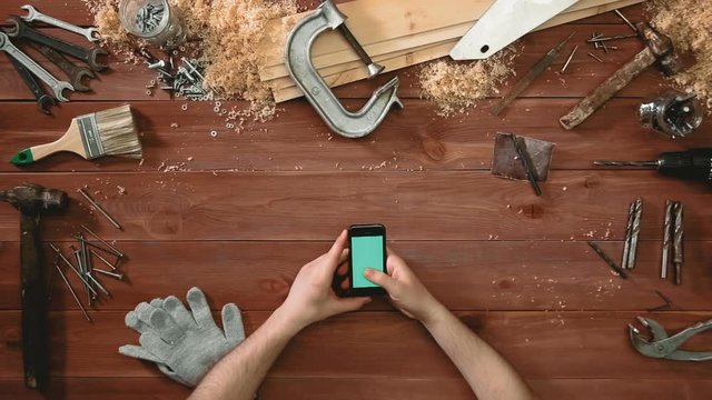 Top view craftsman hands showing multitouch gestures on smartphone with green screen