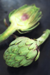 Fototapeta premium Fresh organic opened artichokes over a dark background