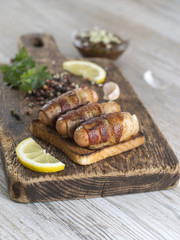 Fried sausages with bacon on a wooden board. 