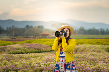 Asian woman photographer is enjoy travel at flower field.