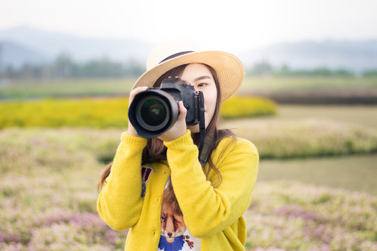 Asian woman photographer is enjoy travel at flower field.