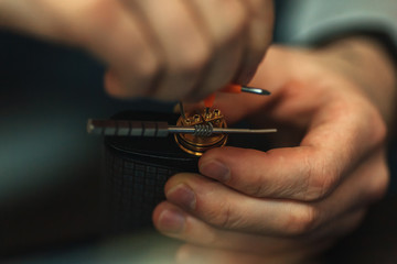 Vape after-sales service of the electronic cigarette. Male hands regulate e-cig coils. Personal vaporizer.