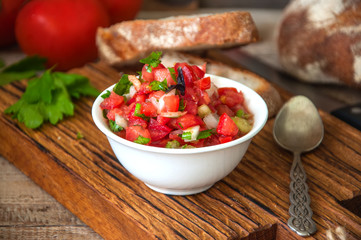 Close up of tomato salsa sauce and ingredients, slices of bread on a wooden background. Rustic style.