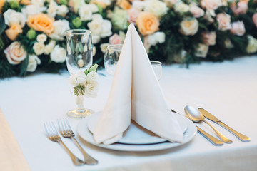 Serviette stands on dinner plates before garland of roses