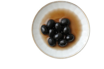 Black olives, lying in a plate, isolated