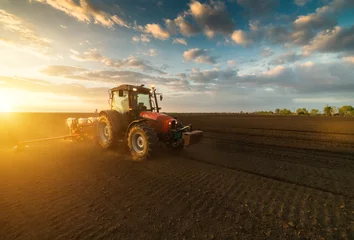 Foto op Plexiglas Tractor Boer met tractor zaaien - zaaien van gewassen op landbouwgebied in het voorjaar