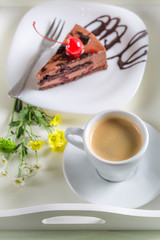 Coffee and chocolate cake with cherries on wooden table
