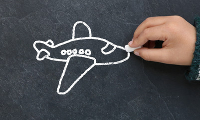 Enfant dessinant un avion sur une ardoise