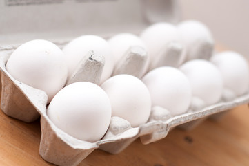 Cardboard egg rack with eggs on white wooden table