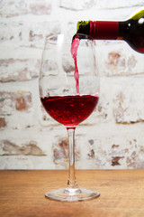 Glass of full bodied red wine being poured