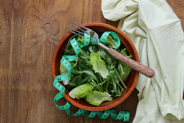 Green salad with measuring tape - diet and healthy food