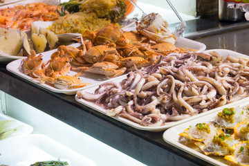 Raw crabs, squids and oysters on white plates