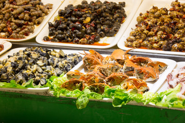 Raw crabs, shellfish and seashells on white plates