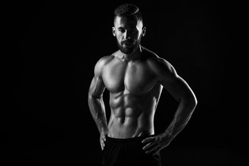 Fototapeta na wymiar The torso of attractive male body builder on black background.