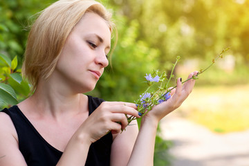 Girl of the European appearance white skin, blonde hair, holding a flower cornflower blue, summer,...
