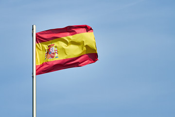 Fototapeta na wymiar In the wind, the Spanish flag waves in the wind against a blue sky.