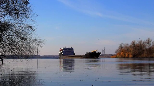 Sunny day. On the river a full calm and tranquility. The ship is moving lengthwise of the Dnieper River in the direction of the dam.