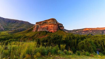 South Africa Drakensberge Golden Gate national park landscape - impressive scenic panoramic nature with red rock landmark, blue sky,trees,sunset, intense colors ,grass
