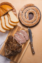 Roasted traditional homemade sausage with spices and herbs. Baked pork with herbs and spice on wooden board and and slices white wheat bread.