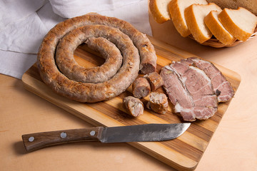 Sliced roasted traditional homemade sausage with spices and herbs. Baked pork with herbs and spice on wooden board and and slices white wheat bread.