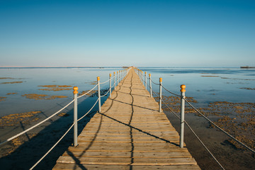 Pier in the Red sea in resort. Summer vacation on Red sea. View at a clear sea with turquoise water in windless conditions. Summer vacation at a sea coastline in an exotic country.